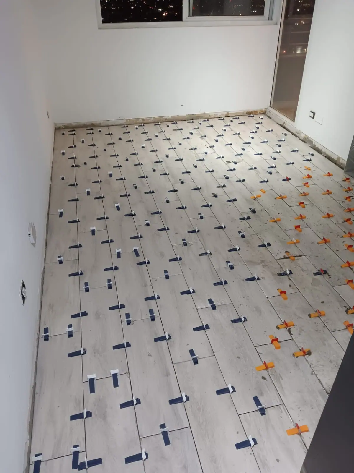 Porcelánico de gran formato en instalación, con crucetas y cuñas niveladoras puestas entre pieza y pieza.