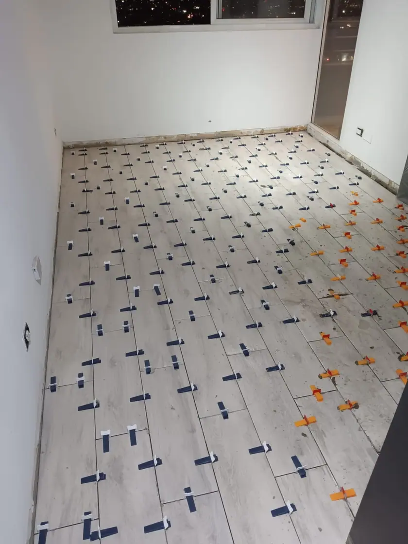 Porcelánico de gran formato en instalación, con crucetas y cuñas niveladoras puestas entre pieza y pieza.